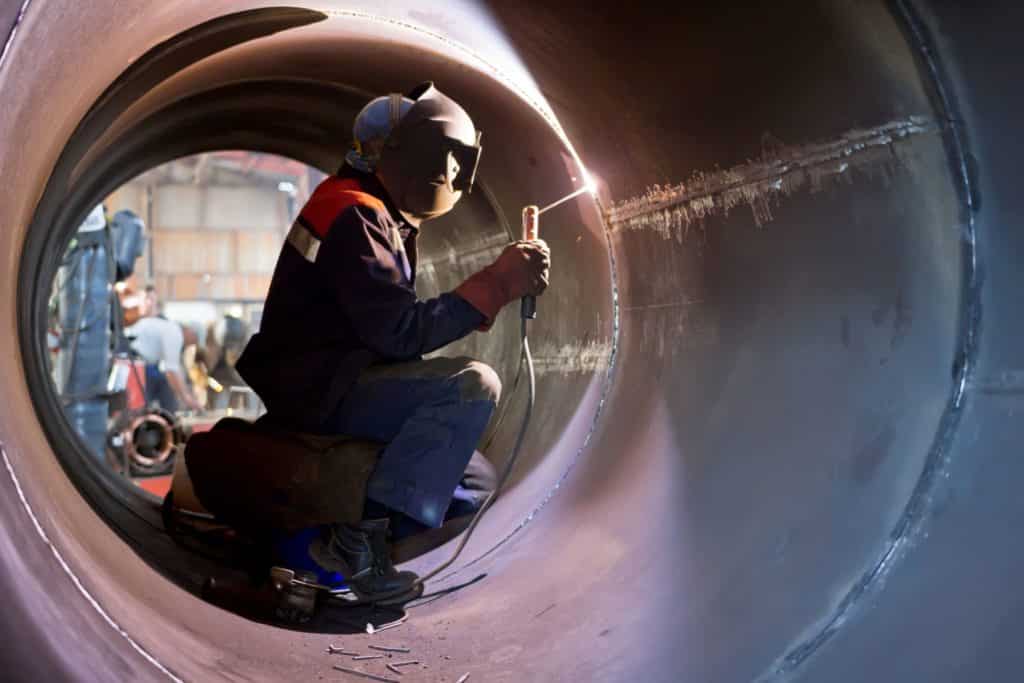 welder working inside big pipe of prefabricated pipe spools