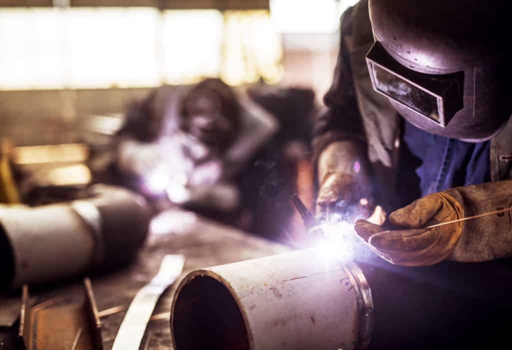 closeup of welder working on a portion of prefabricated pipe spools